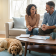 Pet owner discussing a pet-sitting arrangement with a sitter while their dog relaxes nearby